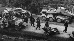 Greek prisoners of war march past German armoured cars.