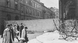 Polish civilians pass the wall of the Jewish ghetto in Warsaw.